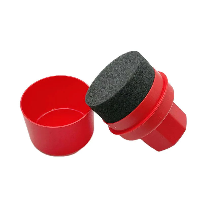 Hand-held black and red car tyre polishing sponge brushes with lids on a garage workbench.