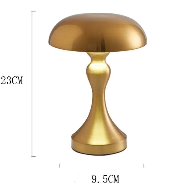Metallic USB-rechargeable LED desk lamp with touch control for three light colours on a wooden desk.