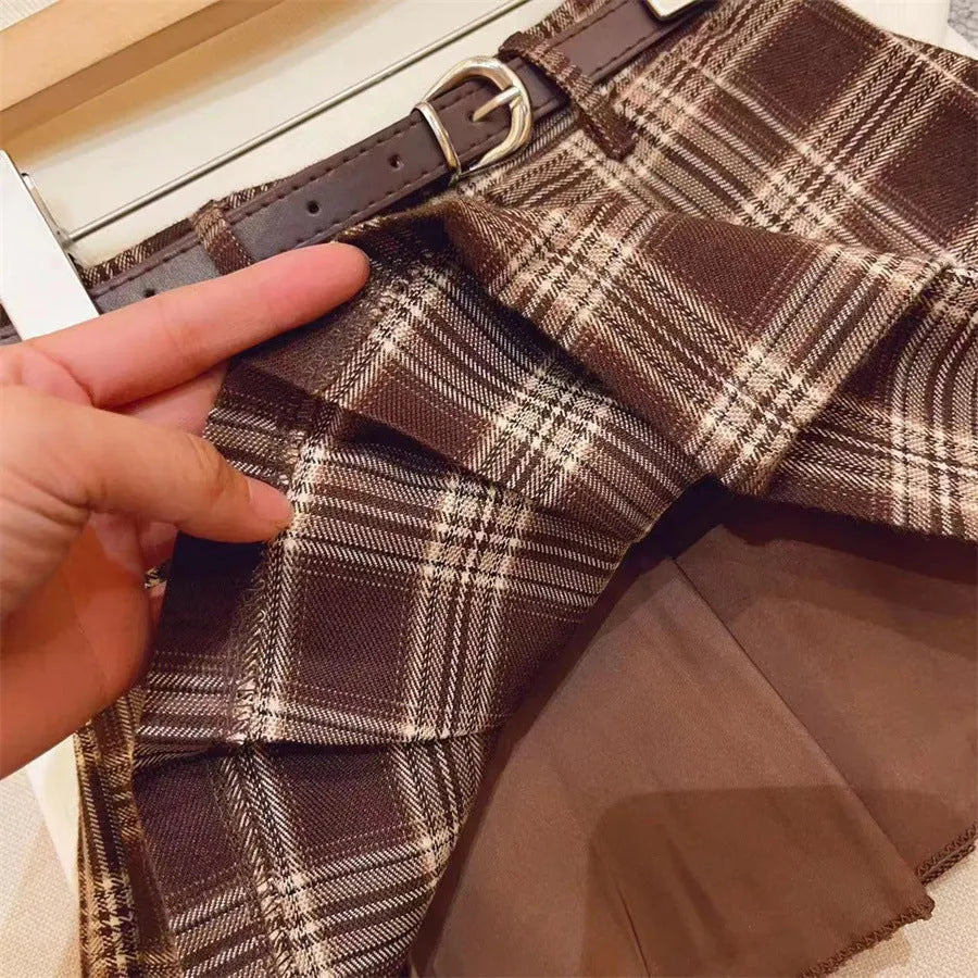 Girls plaid pattern pleated A-line skirt in cotton blend fabric on a hanger.