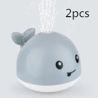 Whale-shaped electric bath toy spraying water with flashing lights, on a blue base.