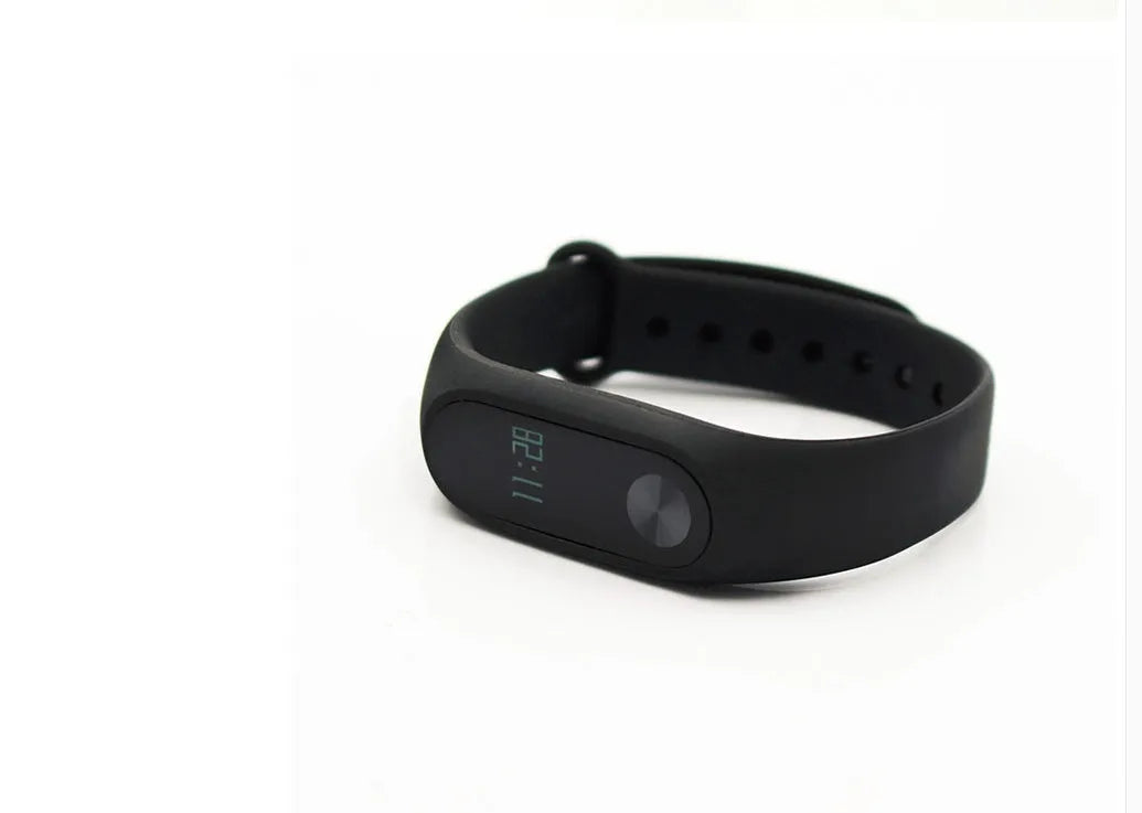 Xiaomi Mi Band 2 black smartband on wrist showing OLED display with heart rate and step count.