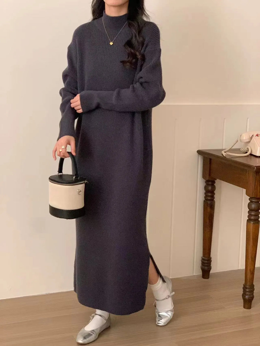 Woman wearing a beige high-waist knitted midi dress with long sleeves and a half turtleneck neckline.