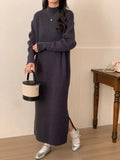 Woman wearing a beige high-waist knitted midi dress with long sleeves and a half turtleneck neckline.