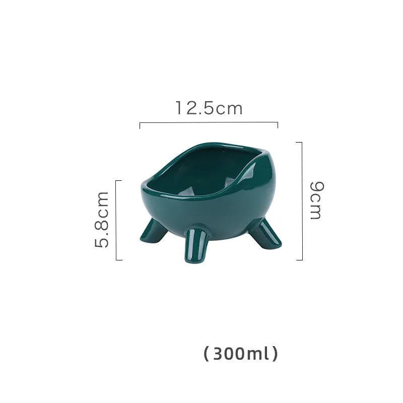 Green ceramic cat food bowl with four-leg stability base on wooden floor