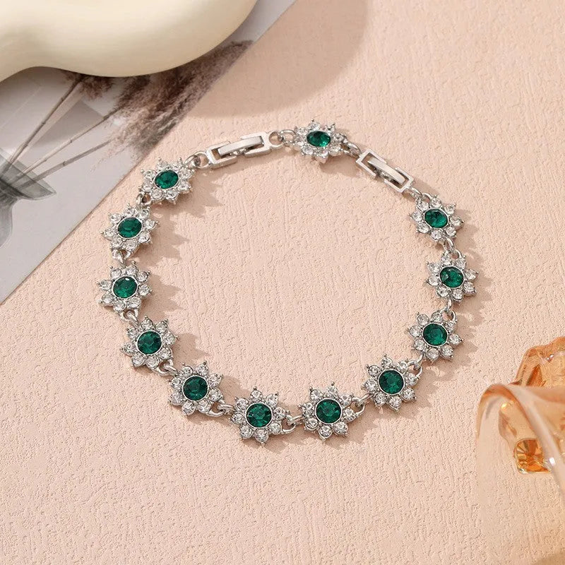 A gold or silver electroplated zinc alloy flower bracelet with coloured gems.
