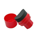 Hand-held black and red car tyre polishing sponge brushes with lids on a garage workbench.