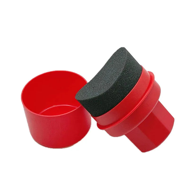 Hand-held black and red car tyre polishing sponge brushes with lids on a garage workbench.