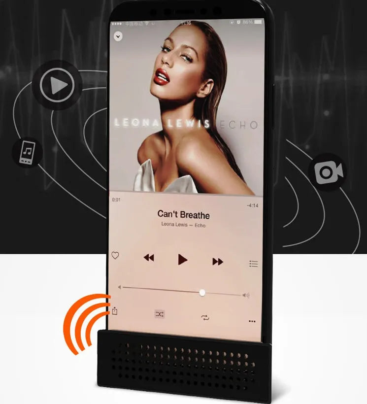 A portable black ABS plastic phone amplifier holder on a desktop, showing a mobile phone inserted for sound amplification.