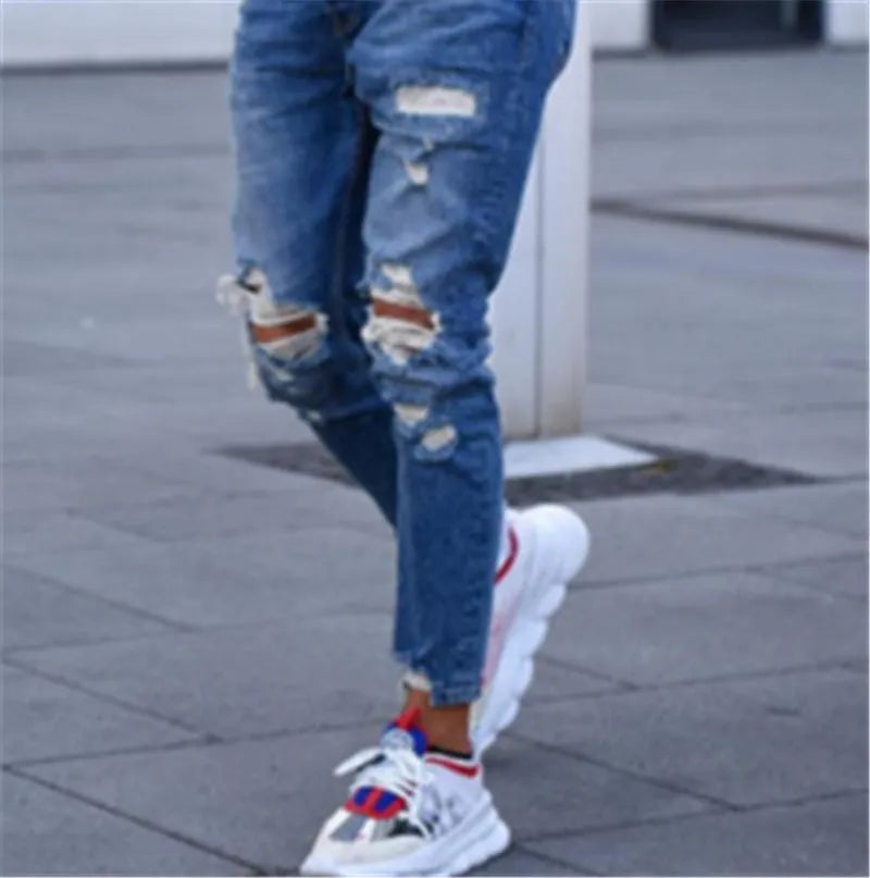 Men's deep blue cotton jeans featuring distressed hole details on the legs.