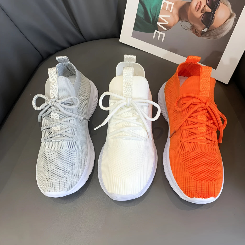 Women's low-top running shoes with mesh lining and Flyknit upper in creamy white, grey, or orange colours