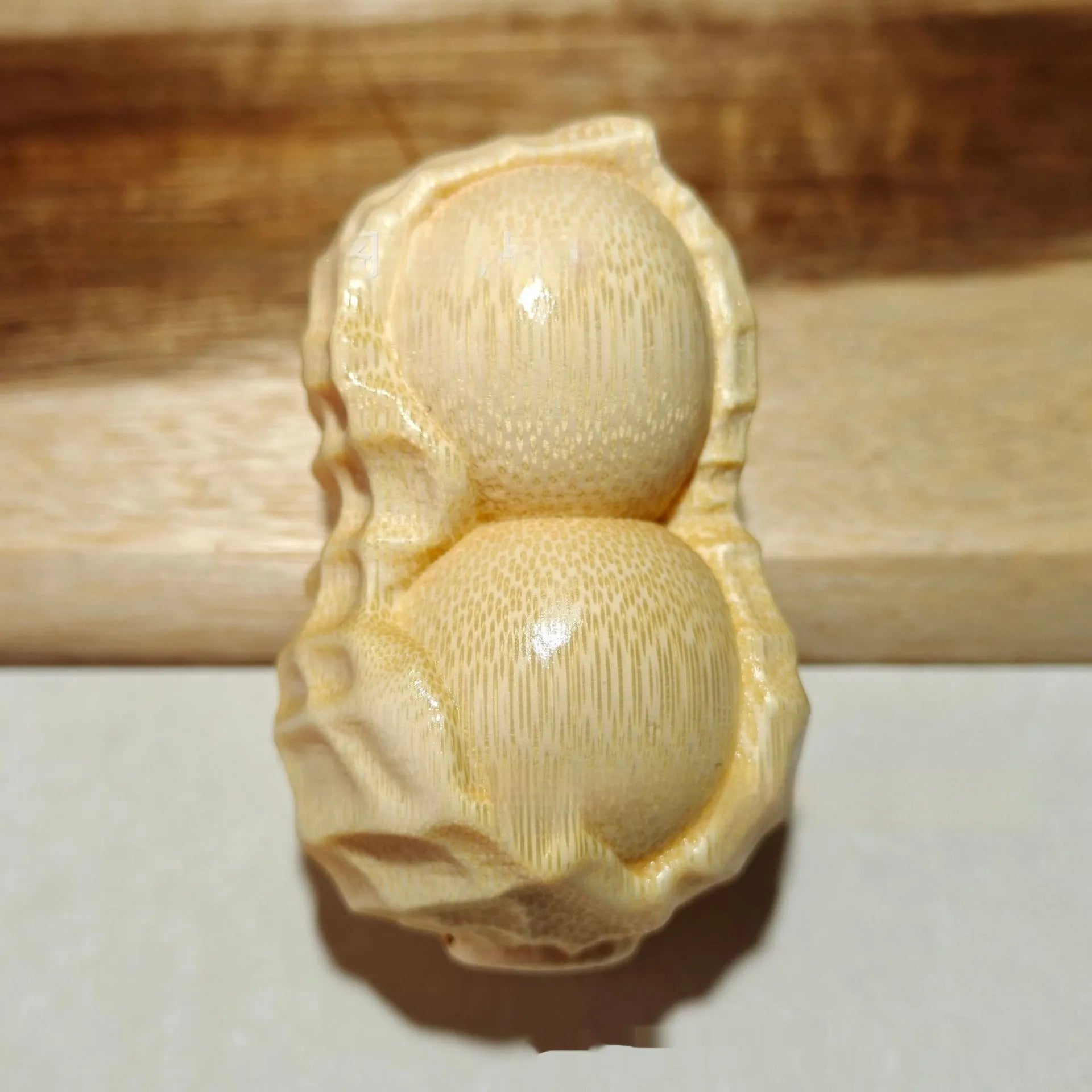 Solid natural bamboo hand-carved peanut ornament on a plain background.