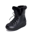 Women's black lace-up winter boots with a platform sole and plush lining on a wooden floor.
