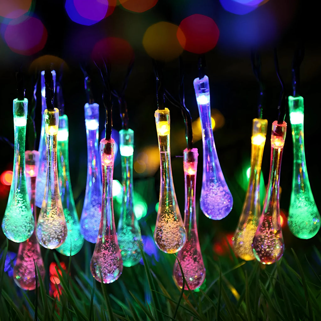 Solar-powered water drop LED string lights in garden with ground spike and bubble pendant design
