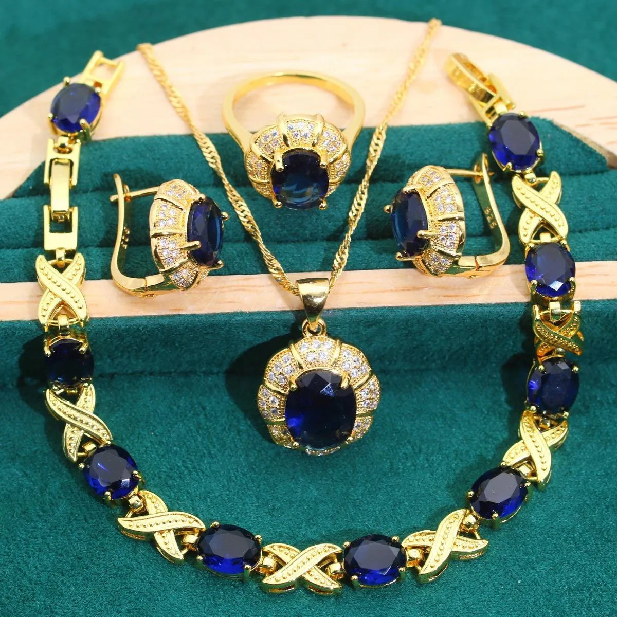Gold coloured necklace, earrings, ring, and bracelet set with blue synthetic cubic zirconia stones.
