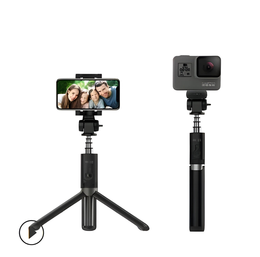 Black Bluetooth selfie stick with extended tripod legs and remote control next to a mobile phone.