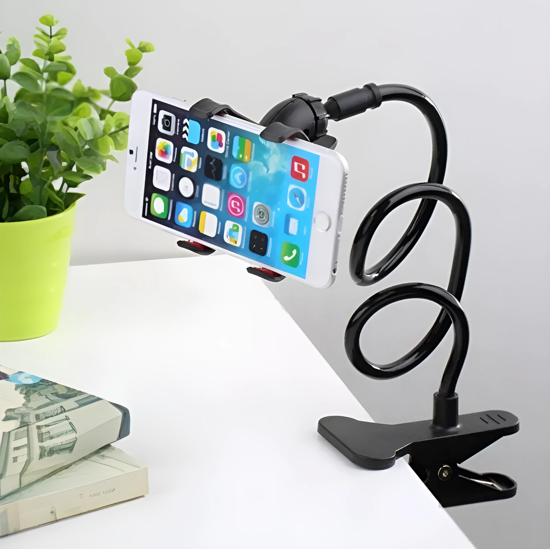 Black portable phone holder with long flexible arm and V-clip on a bedside table
