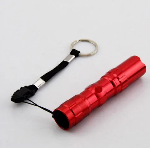 Small black aluminium LED mini flashlight shown next to a AA battery for scale.