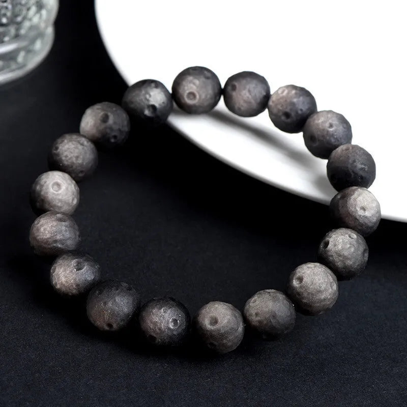 Natural obsidian crater ball bracelet with polished beads in silver or gold meteorite finish.