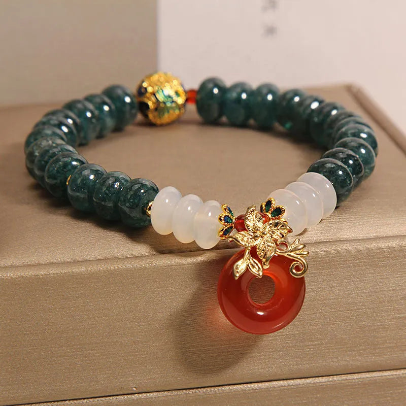 Blue water jade bead bracelet with red agate peace buckle closure and rhinestone details