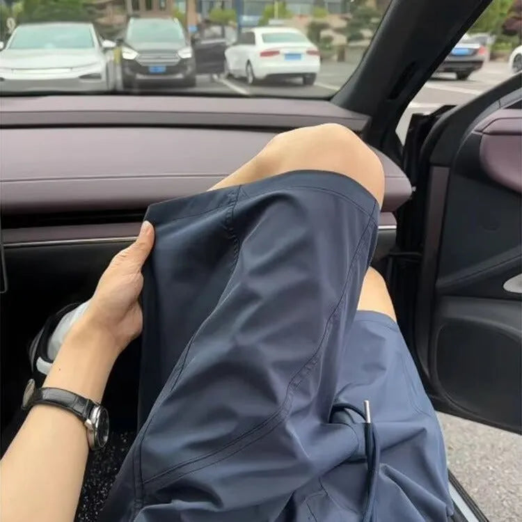 Men's beige polyester sports shorts with elastic waistband, shown alongside black and navy blue colour options.