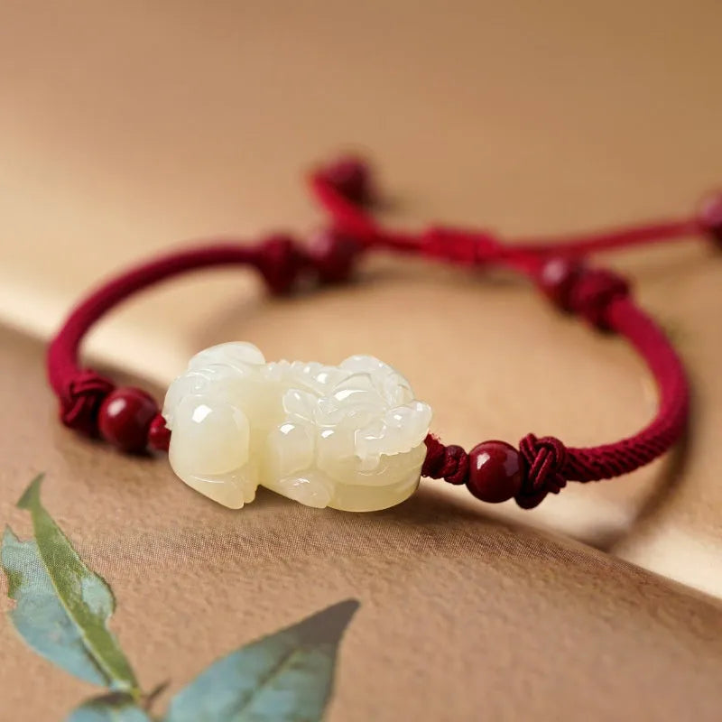 A Hetian jade bracelet with braided black and red rope in a Chinese style design.