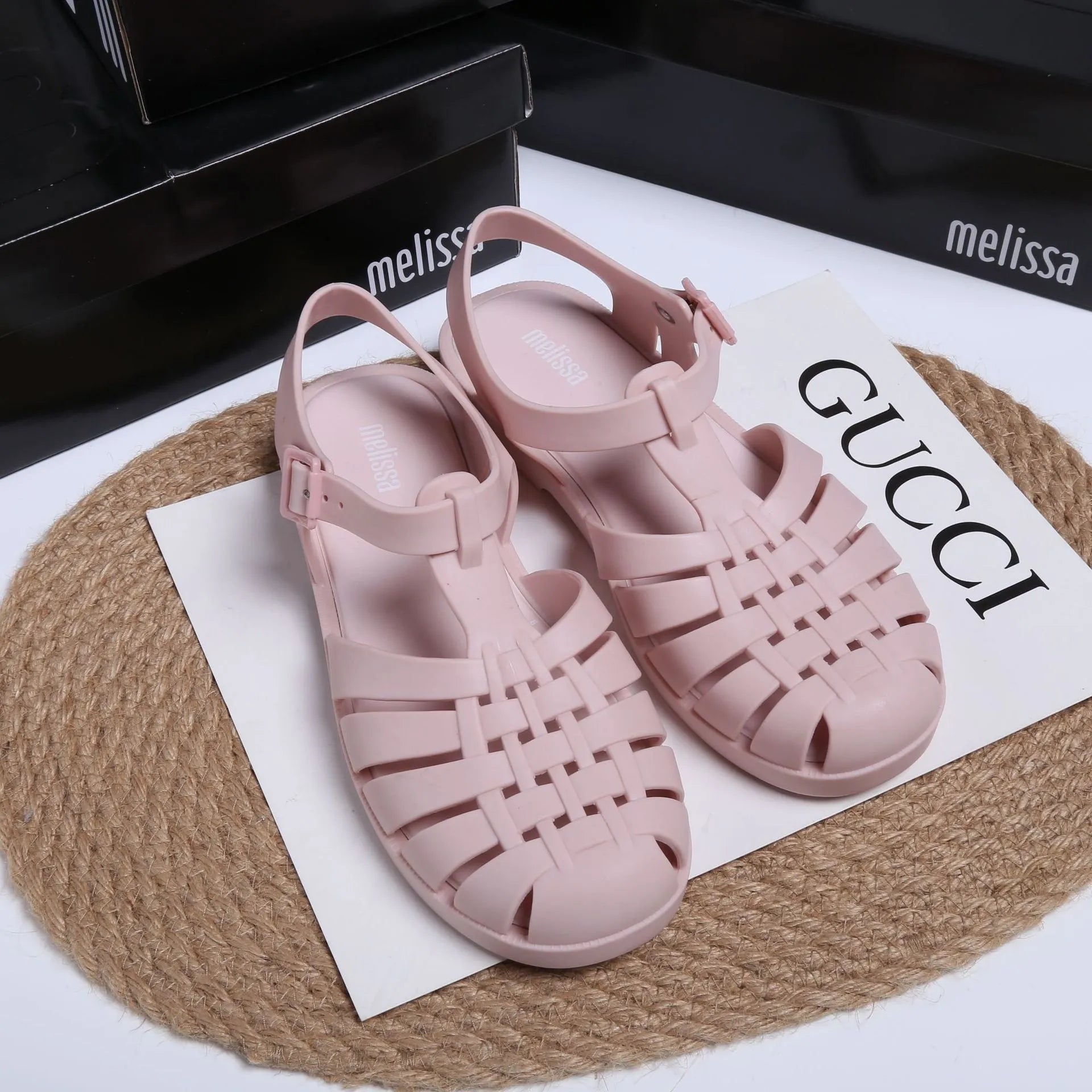 Matte black Roman style sandals with buckle fastening and PVC upper on wooden surface