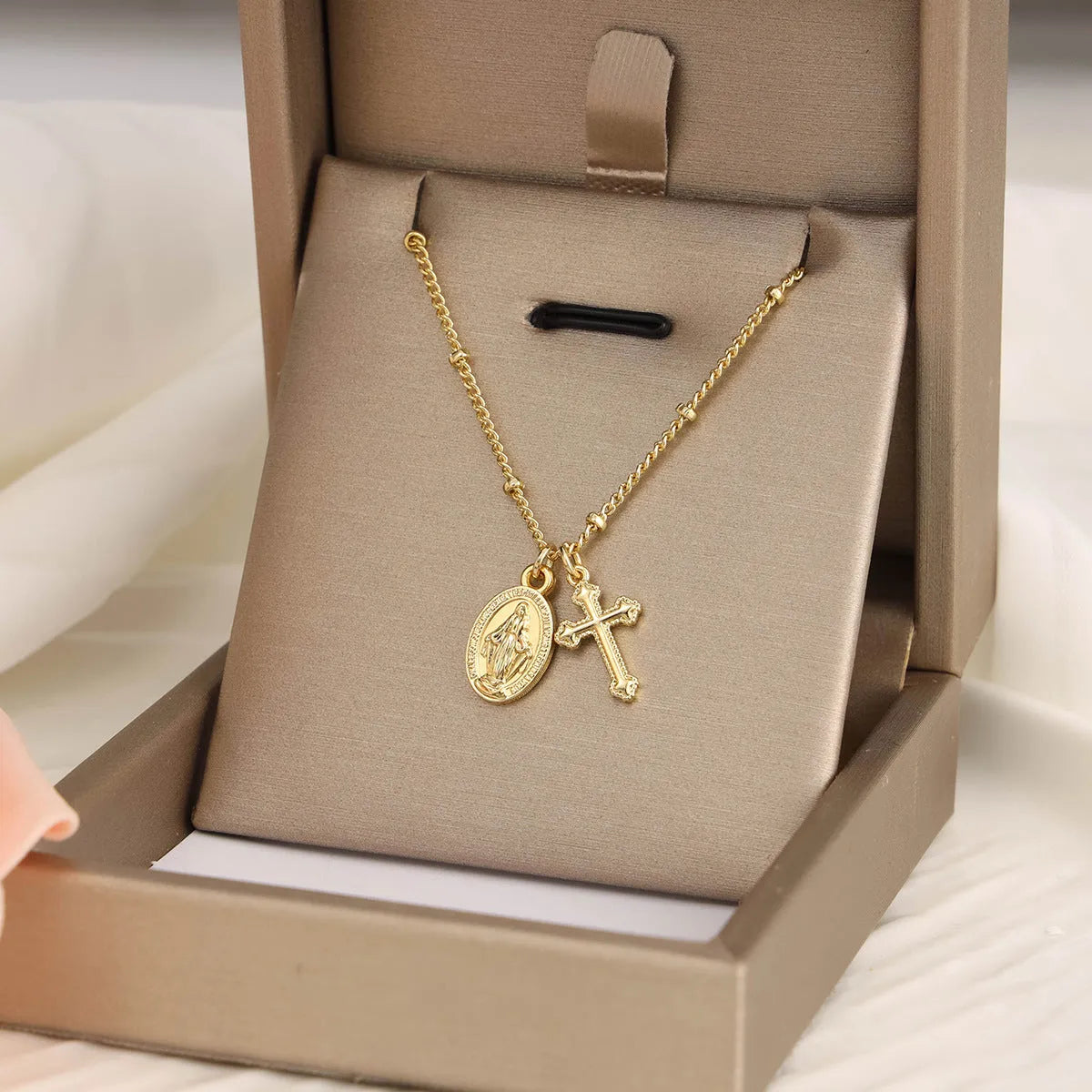 Geometric shaped gold tone pendant necklace with Cross and Virgin Mary ornament.