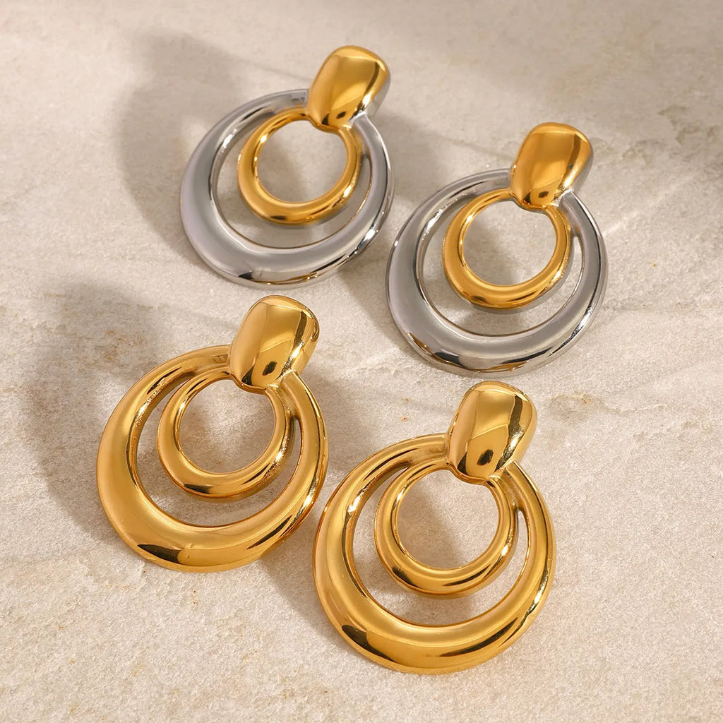 Round gold-coloured geometric hollow stud earrings on a white background.