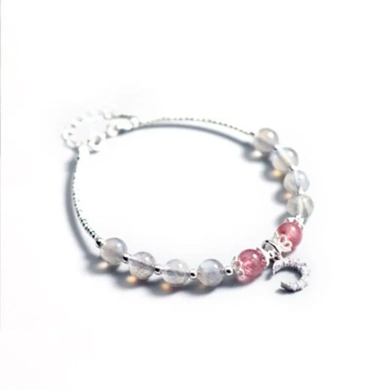 Simple handmade bracelet with round moonstone beads, a small crescent moon charm, and an adjustable metal clasp.