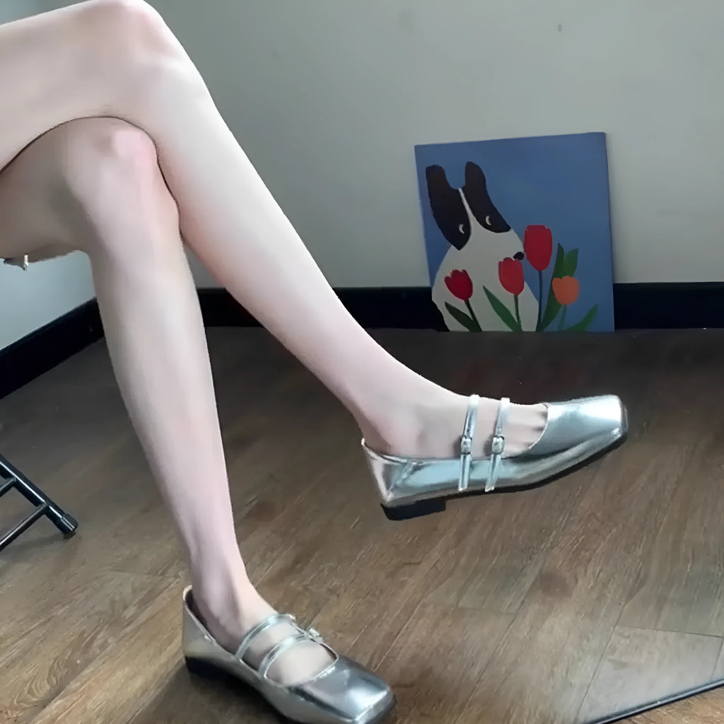 Silver women's Mary Jane ballet flats with cross buckle strap and round toe on flat low heel.
