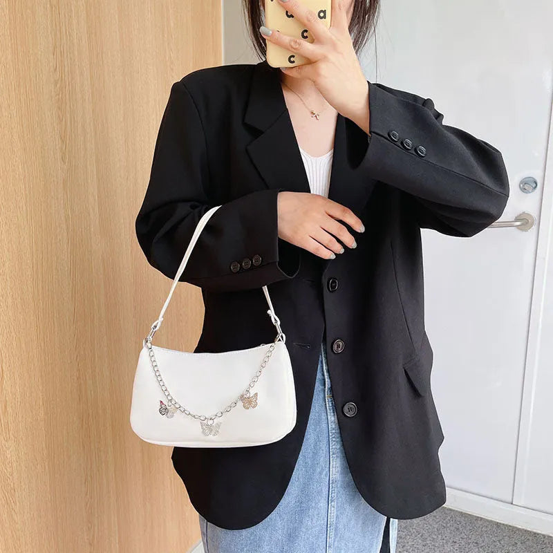 Retro-style square crossbody handbag with a butterfly clasp on its chain strap.