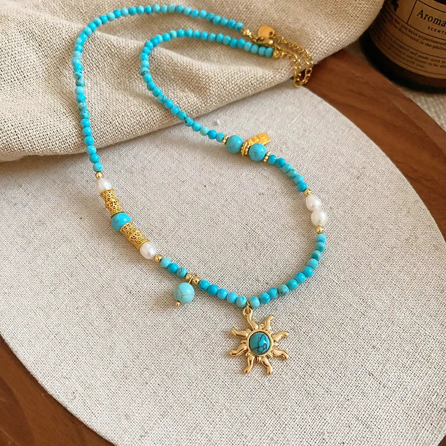Close-up of a freshwater pearl and geometric stone sun necklace on an adjustable clavicle chain.