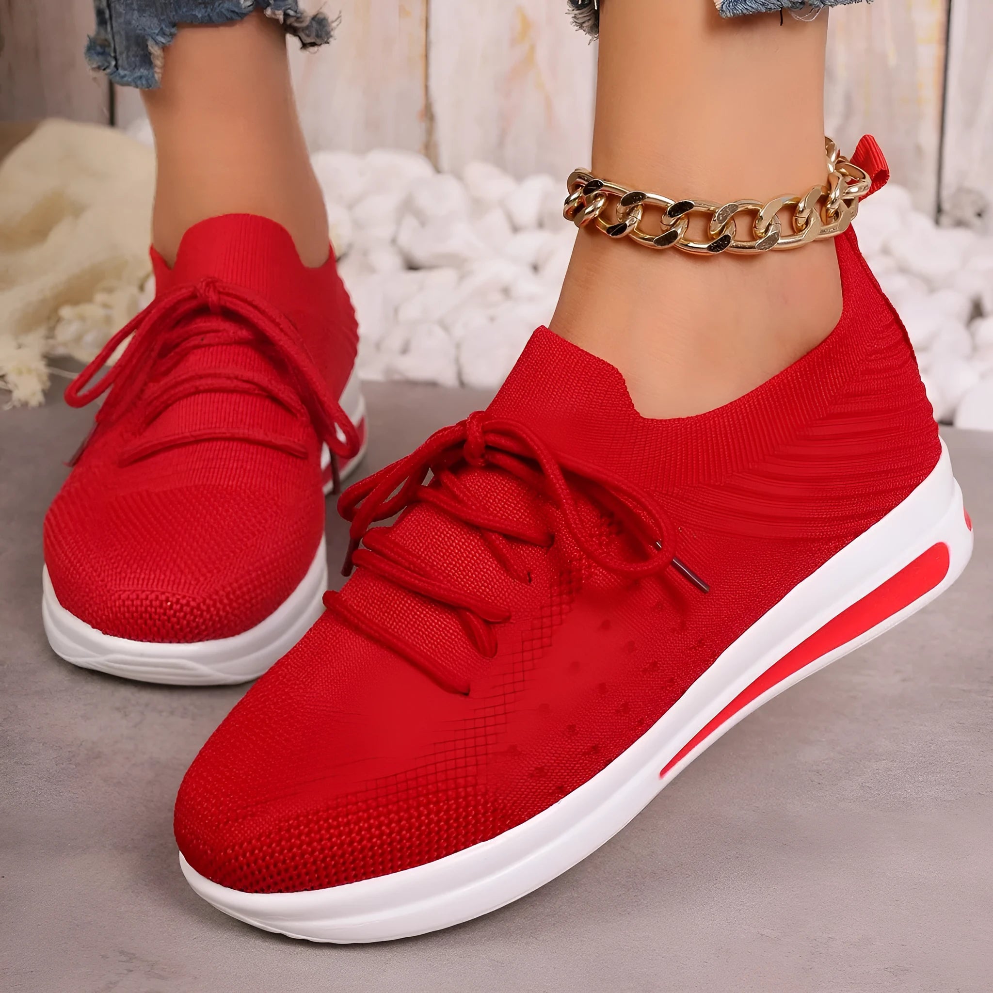 Women's low-top red fly-knit sneakers with round toe and white injection moulded sole on a light background.