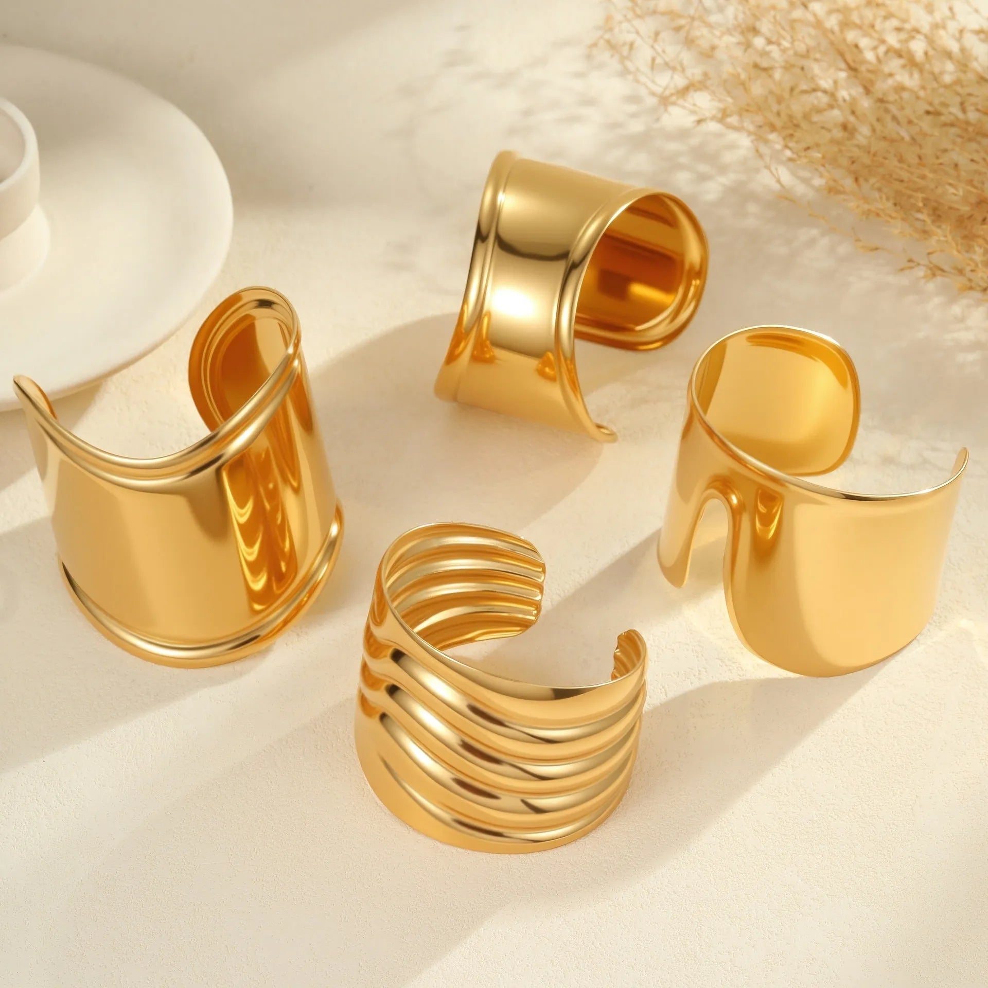 Women's wide stainless steel bracelet with 18K gold plating showing geometric wave patterns