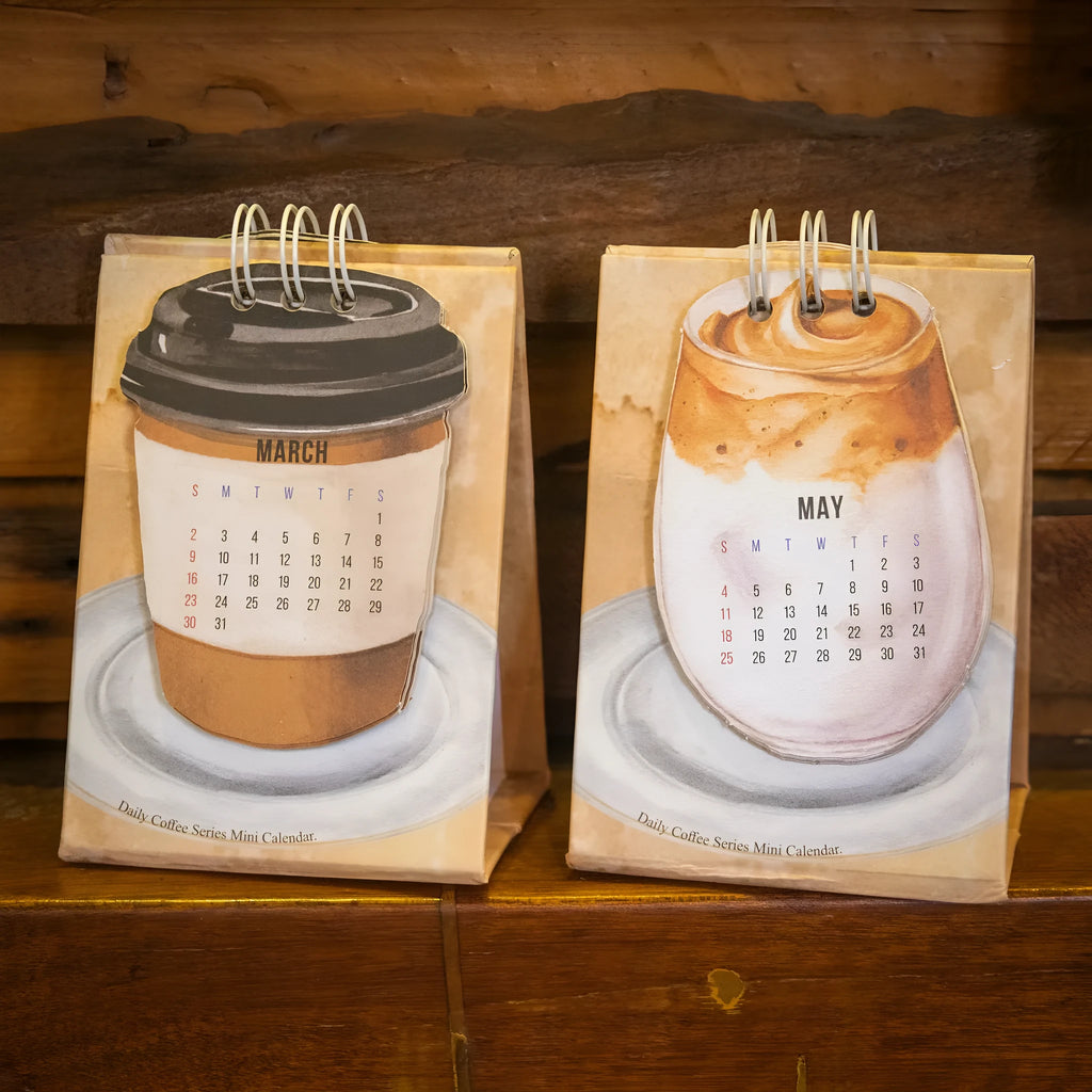 Mini A6 paper desk calendar for 2025 open to a monthly page with coffee-themed design.