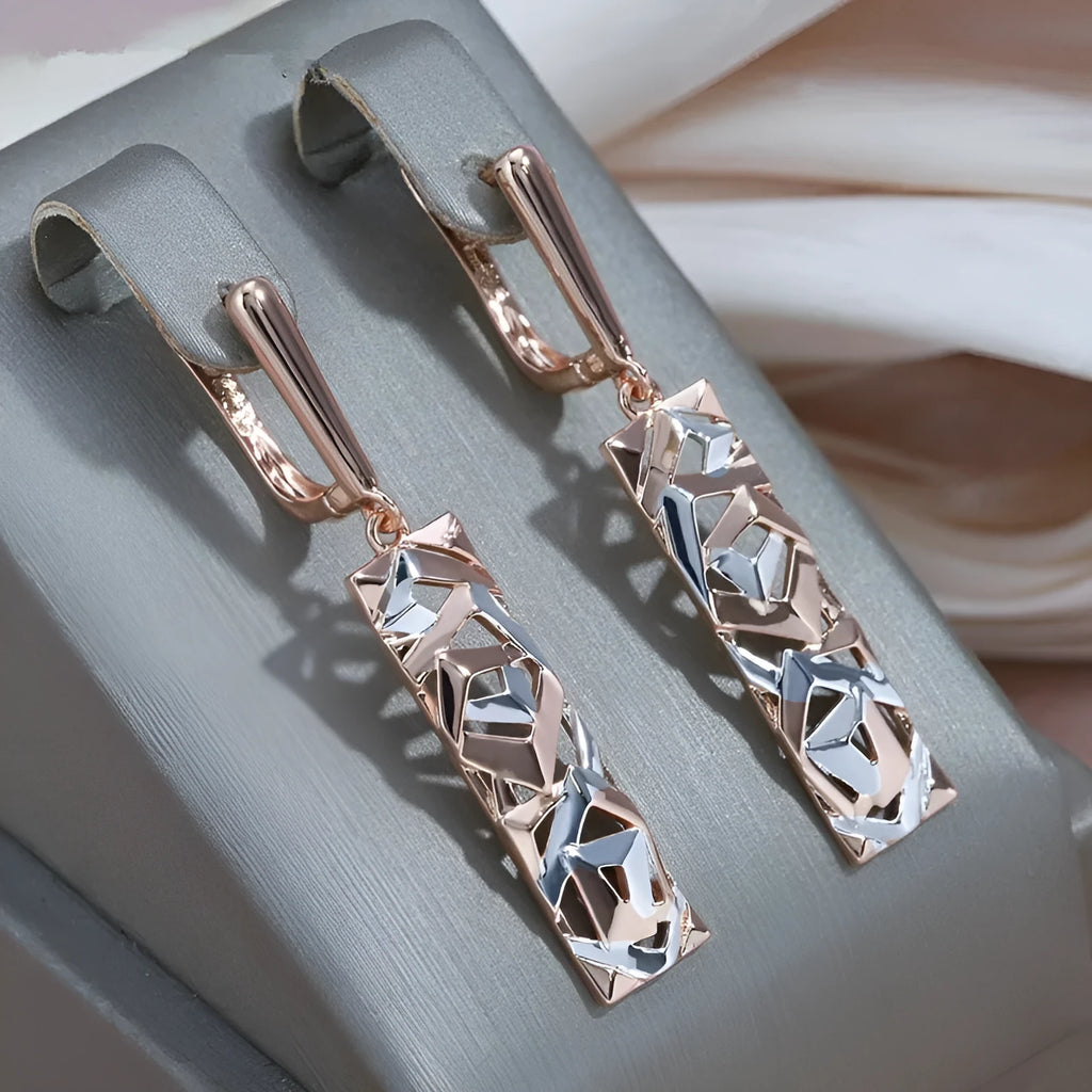 A pair of rectangular hollow stud earrings with a two-tone geometric design on a white background.