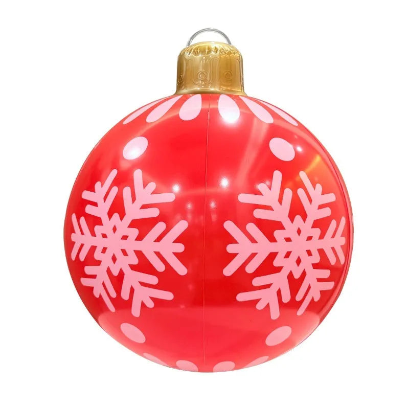 Large red inflatable Christmas ball with snowflake pattern and flash light, shown with a hand pump in a garden setting.