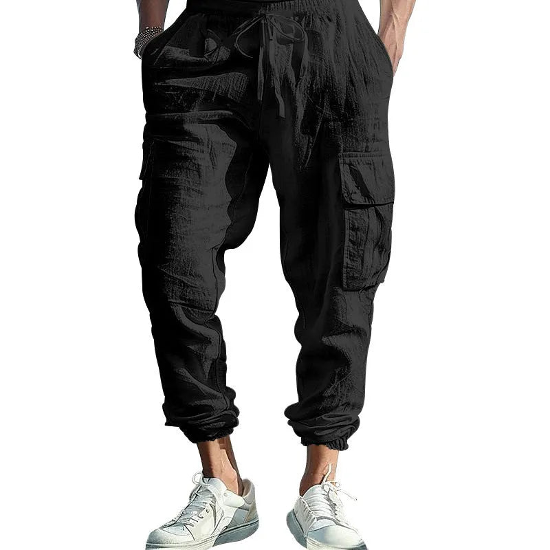Man wearing loose, ankle-tied linen trousers in a solid colour with visible pockets.