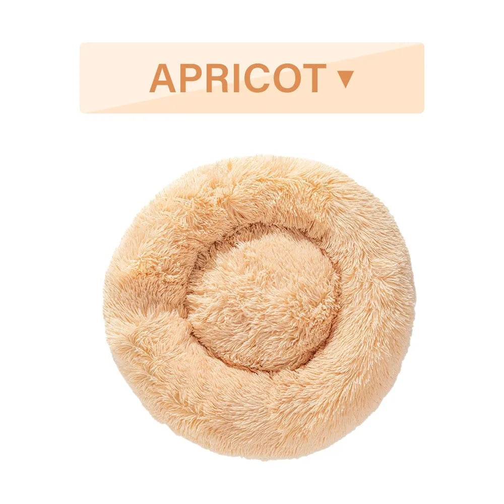 Fluffy donut-shaped dog bed in long plush material, shown in a light grey colour with a raised edge.