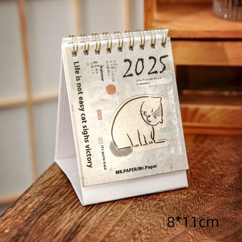 Mini A6 paper desk calendar for 2025 open to a monthly page with coffee-themed design.