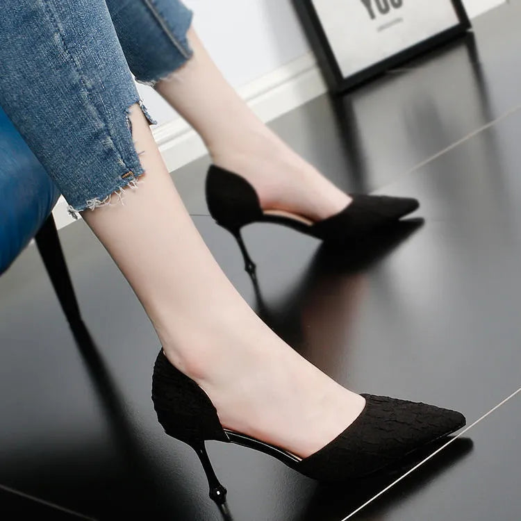 Women's black pointed toe stiletto sandals with a high heel on a plain background.