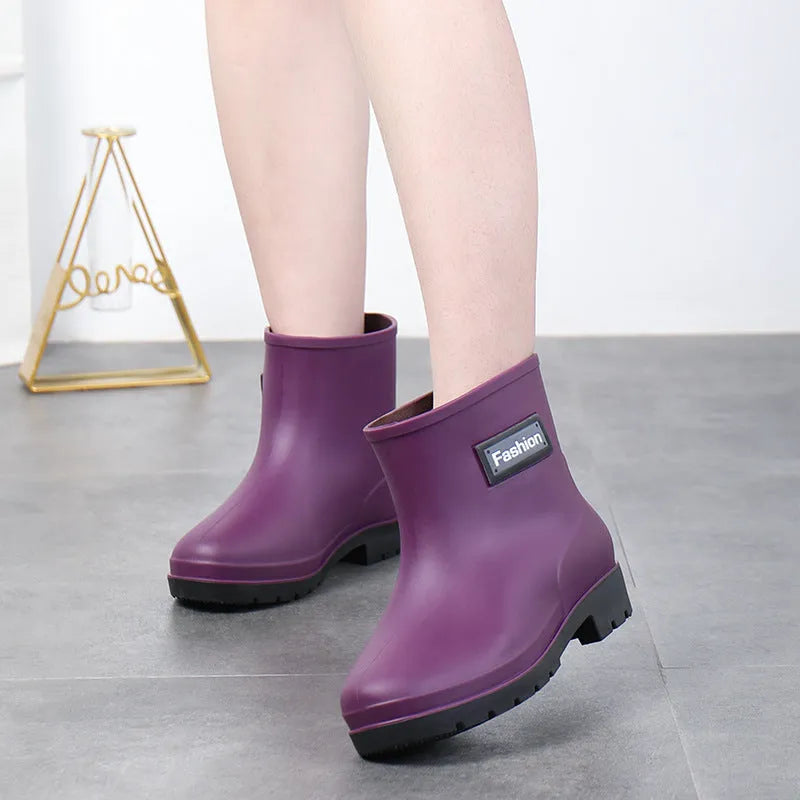 Women's mid-calf PVC rain boot in black on a wet surface.