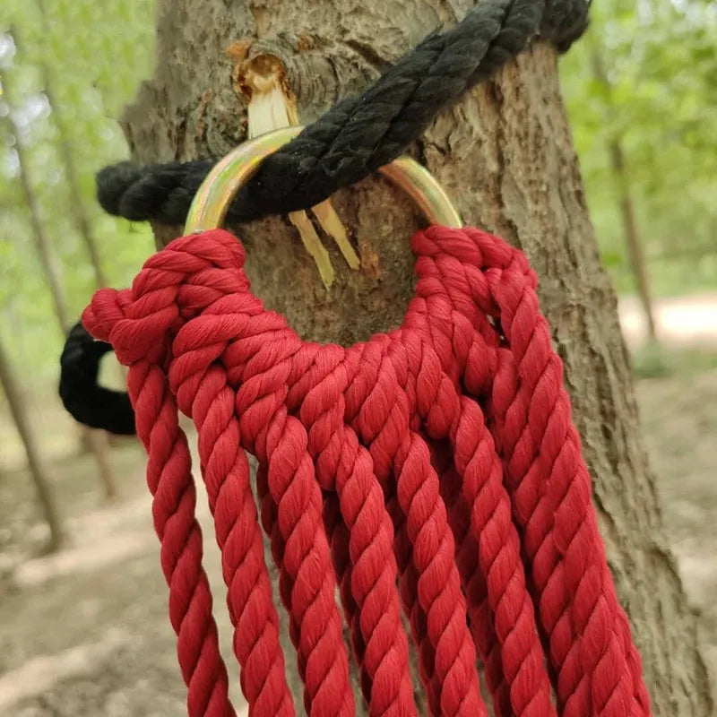 Nylon rope mesh hammock hung between two trees with tying rope visible