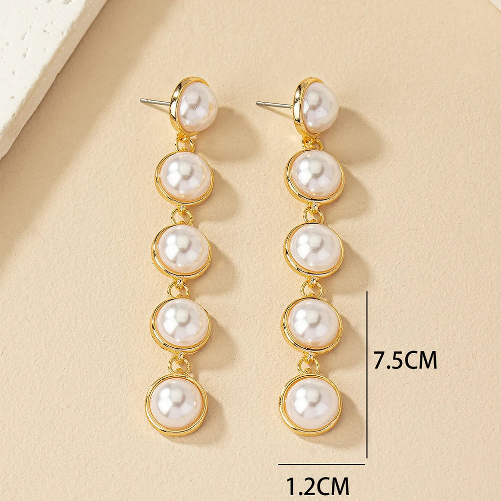 White metal drop tassel earrings with pearl water flow design on display