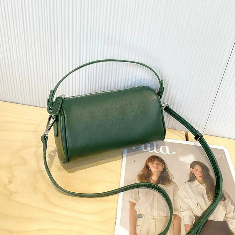 Vegetable-tanned leather crossbody phone bag with cylindrical shape and visible sewing thread detailing