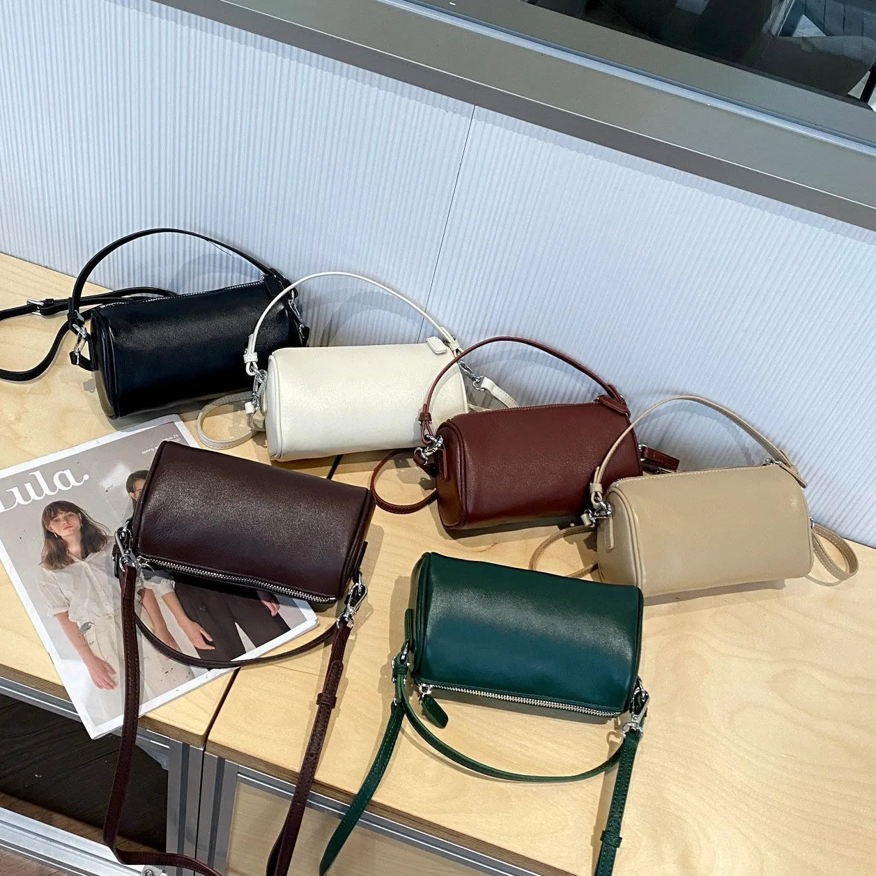 Vegetable-tanned leather crossbody phone bag with cylindrical shape and visible sewing thread detailing