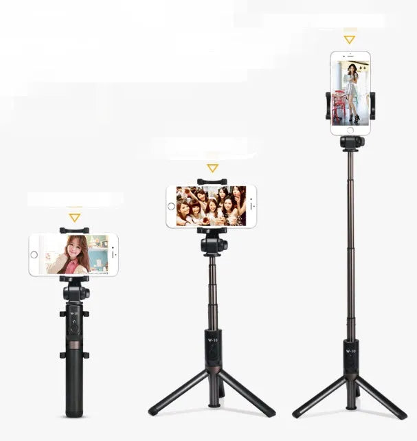 Black Bluetooth selfie stick with extended tripod legs and remote control next to a mobile phone.