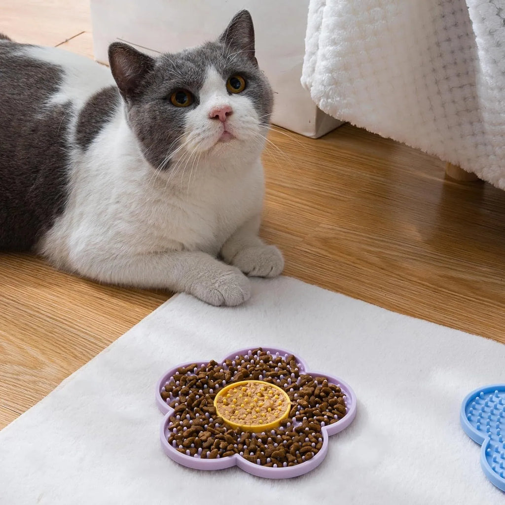 Flower-shaped blue silicone dog licking mat with suction cups on a smooth tile surface.