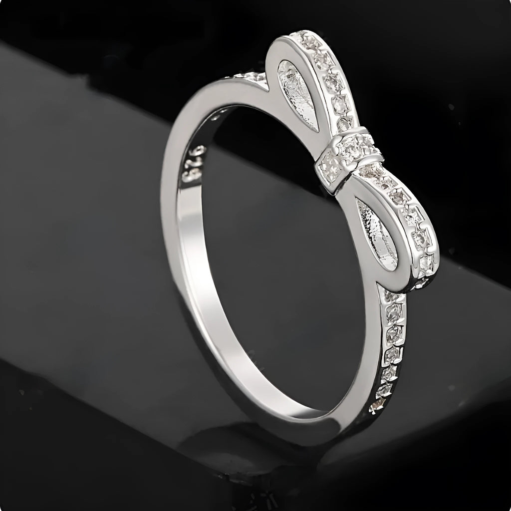 Silver bow-shaped rhinestone ring with zircon crystals on finger