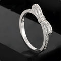 Silver bow-shaped rhinestone ring with zircon crystals on finger